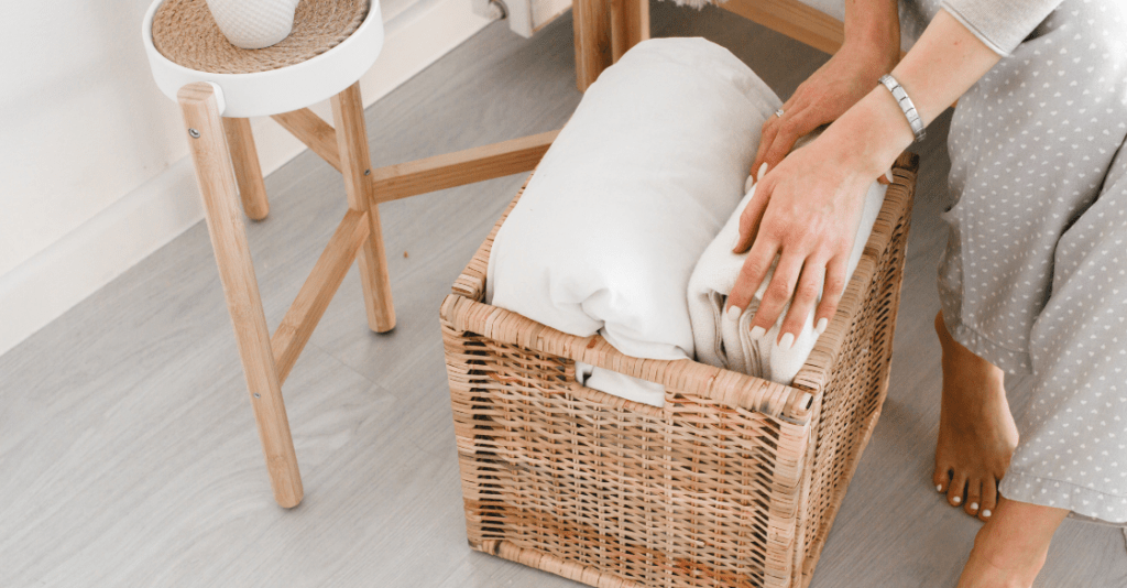Woman decluttering by hiding blankets in a basket